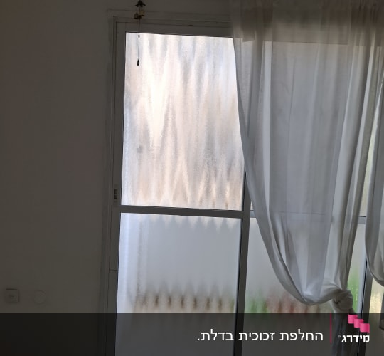 חלון זכוכית עם וילון לבן קשור בצד